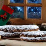 Stollen mit Puderzucker und Kerze am Fenster