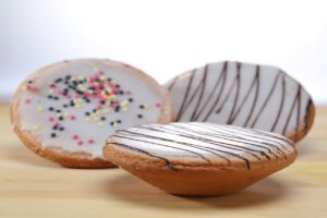 Drei Amerikaner mit Zuckerguss, Schokolade und bunten Streuseln